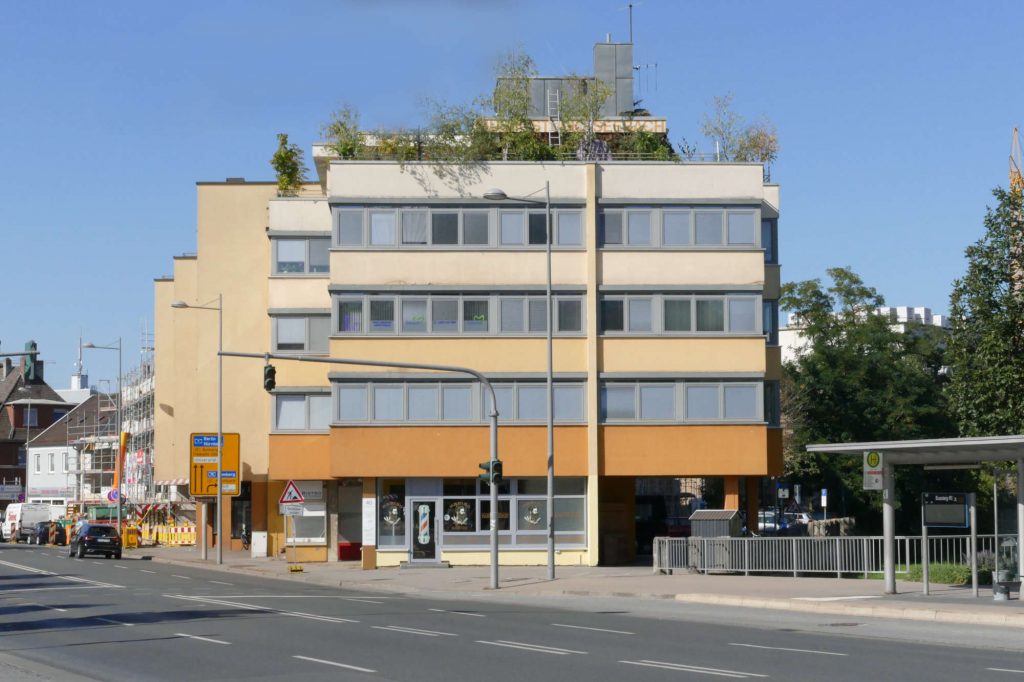 Das Bürogebäude der a.k.m.: Ein vierstöckiges, quadratisches Gebäude an einer Straße